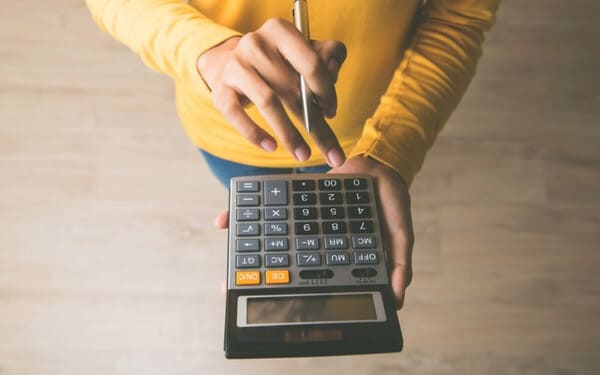 Pessoa a organizar despesas com calculadora e papéis